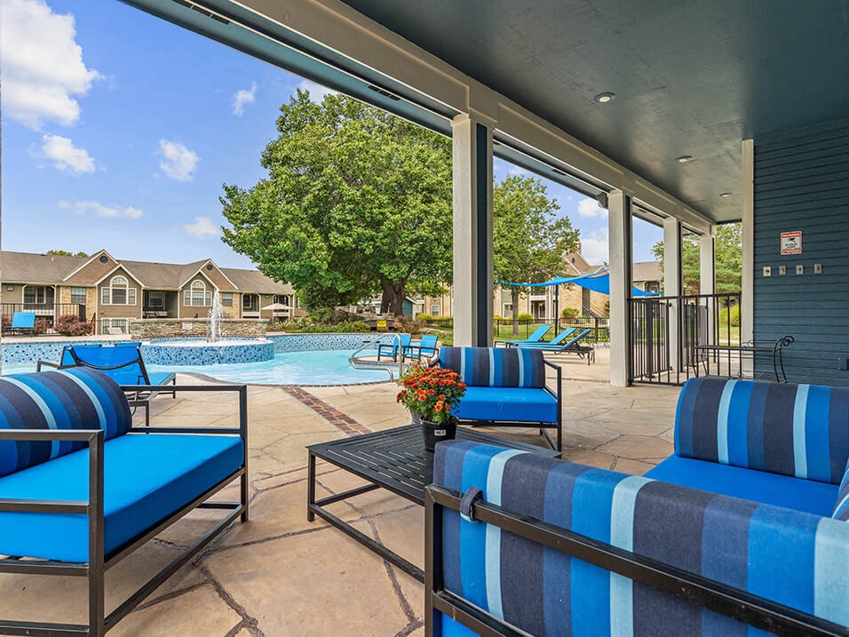 a balcony with blue chairs and a view of a yard and trees