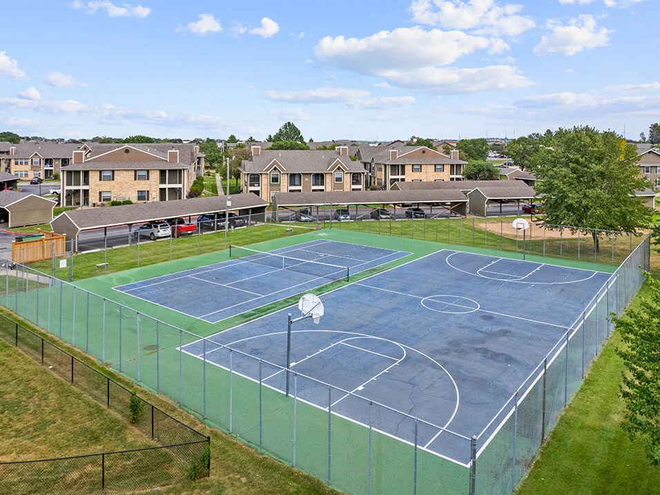 a tennis court with apartments in the background