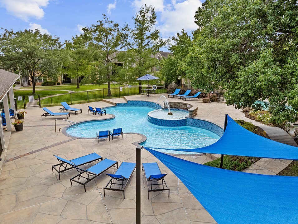 a resort style pool with blue umbrellas and chairs