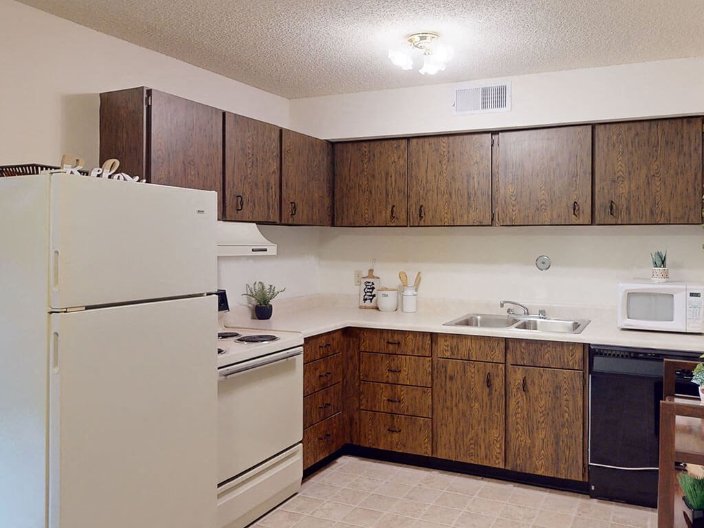 apartment kitchen with white appliances and wooden cabinets