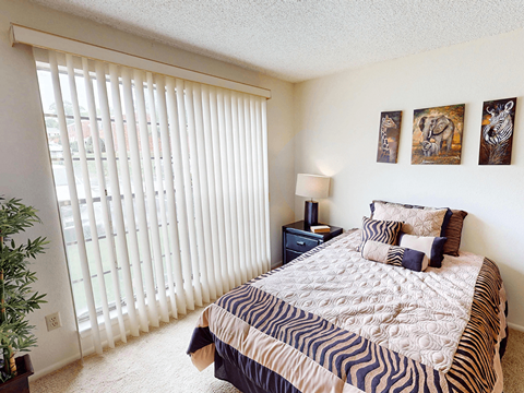A bedroom with a bed, nightstand, and pictures on the wall.