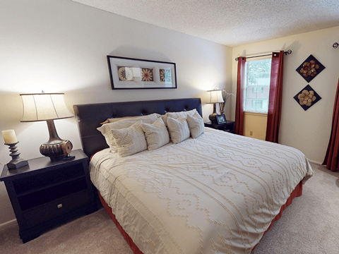 A bedroom with a large bed and a nightstand with a lamp.