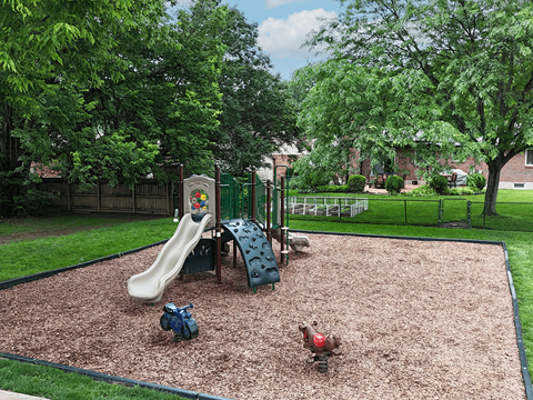 A playground with a slide, swings, and a seesaw.