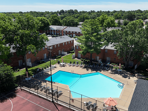 A pool surrounded by chairs and trees in a residential area.