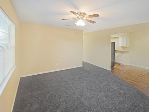 A room with a ceiling fan and carpeted floor.