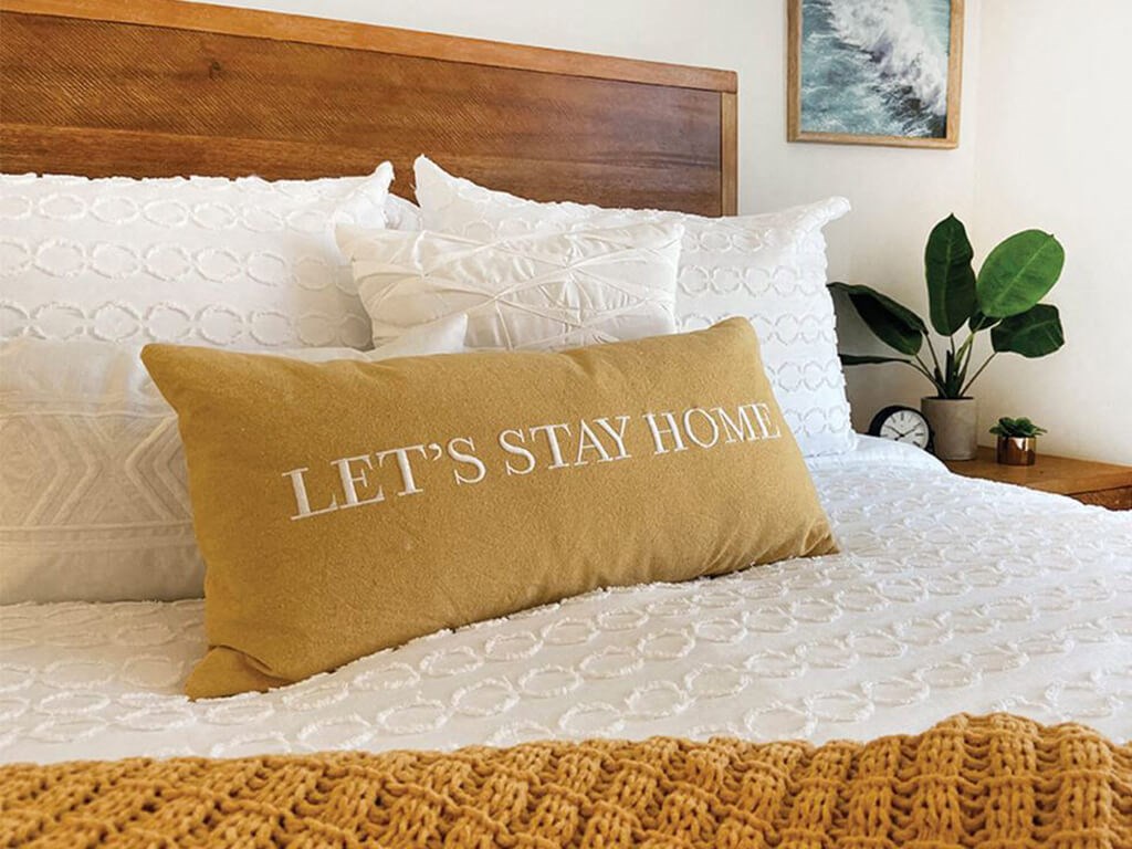 lets stay home pillow on a bed
