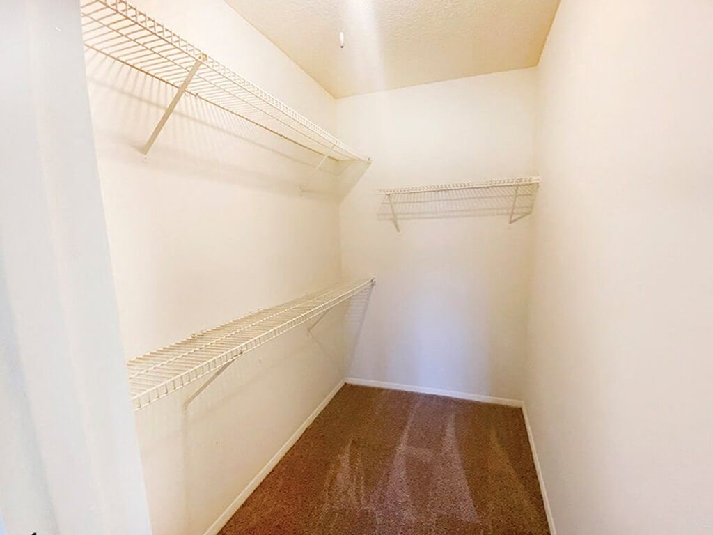 a walk in closet with shelves and a white wall