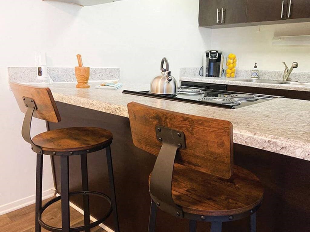a kitchen with two stools in front of a counter