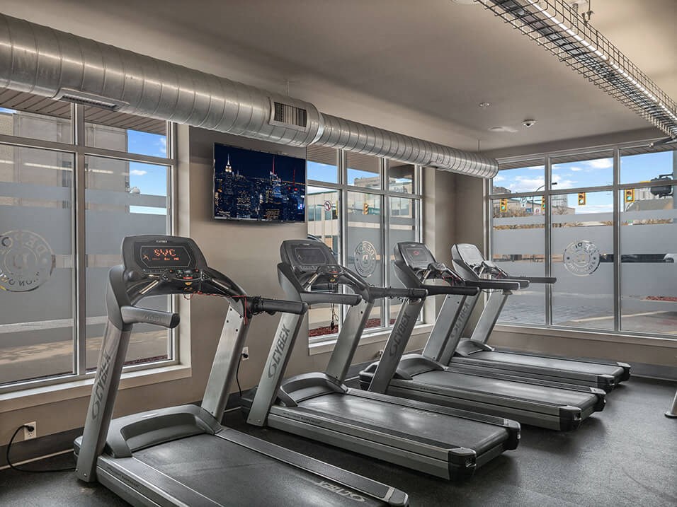 a gym with four treadmills and a large window