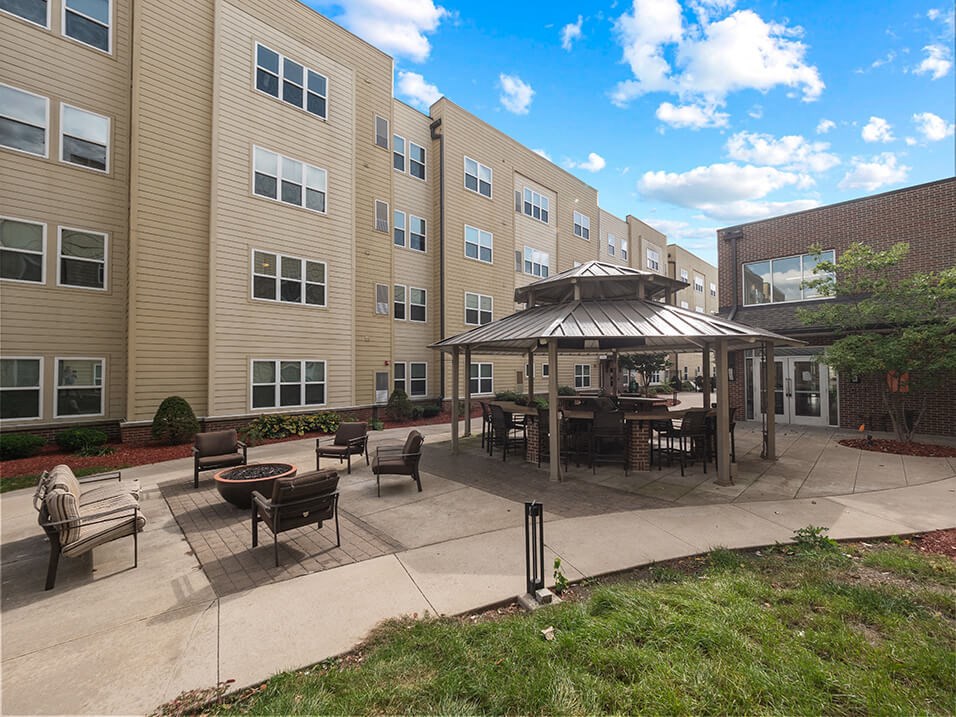 an outdoor patio with a firepit and gazebo in front of an apartment building