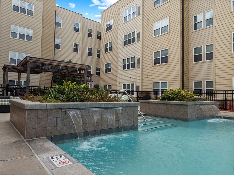 a pool with a waterfall in front of a building