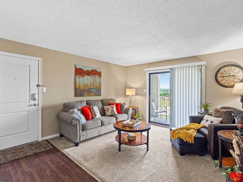 a living room with a couch and a chair and a door to a balcony