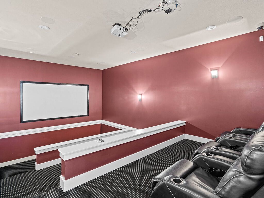 a theater room with leather chairs and a white screen