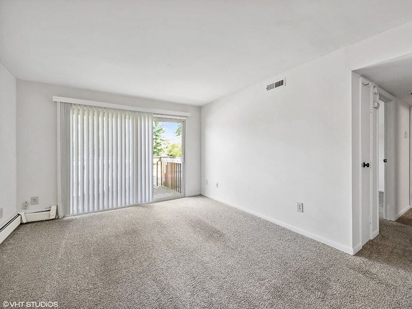an empty living room with a sliding glass door to a balcony