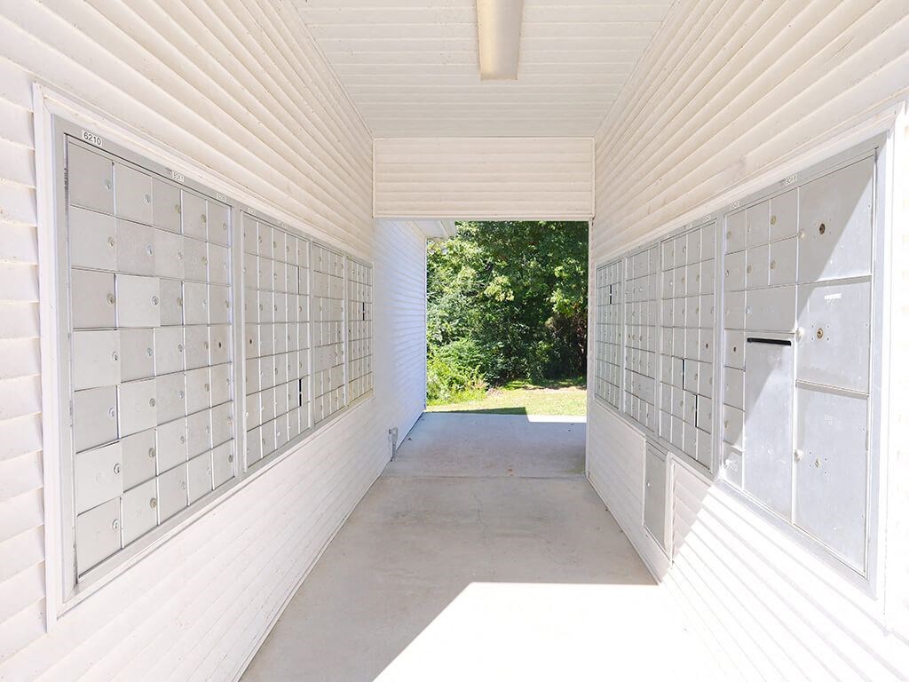 A long white hallway with mailboxes on the wall.