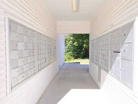 A long white hallway with mailboxes on the wall.
