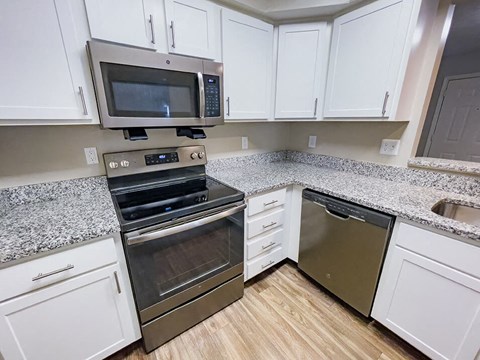 a kitchen with white cabinets and stainless steel appliances