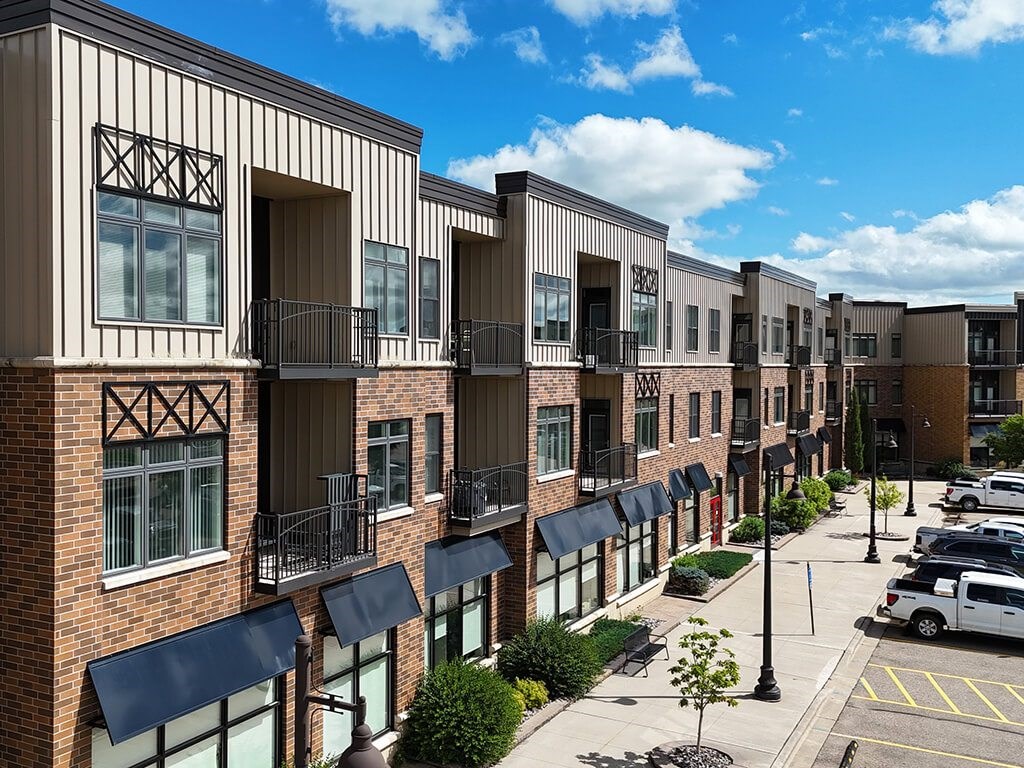 A row of modern townhouses with balconies and black awnings.