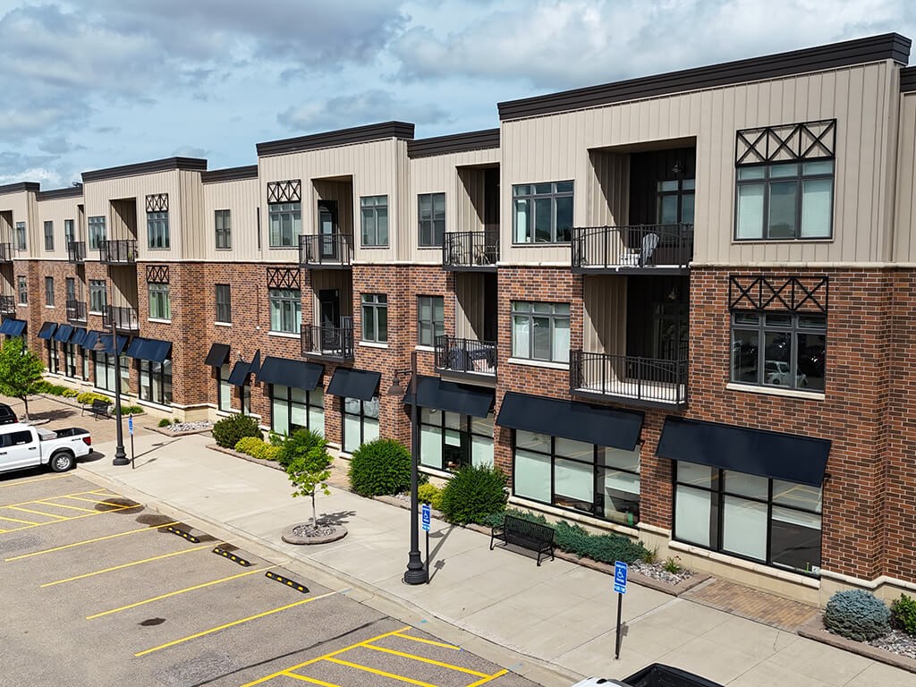 A row of apartment buildings with balconies and black awnings.