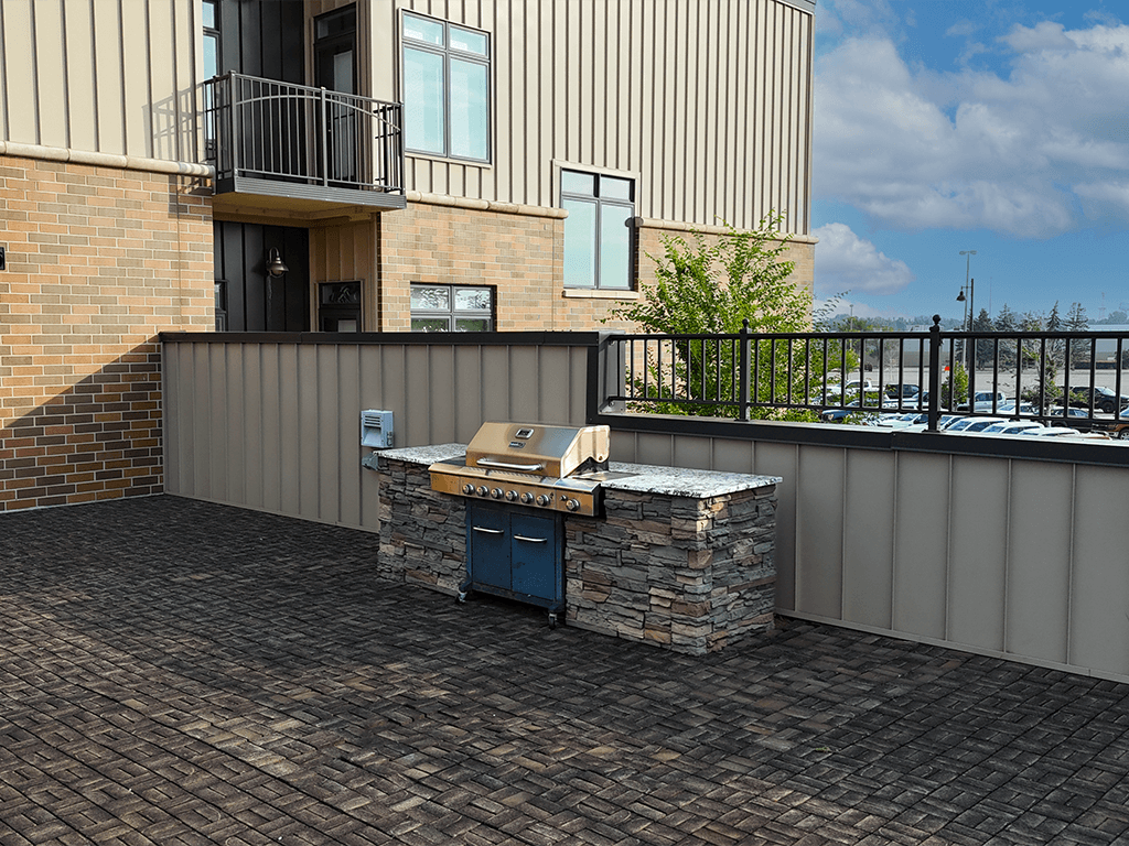 A patio with a barbecue grill and a stone wall.