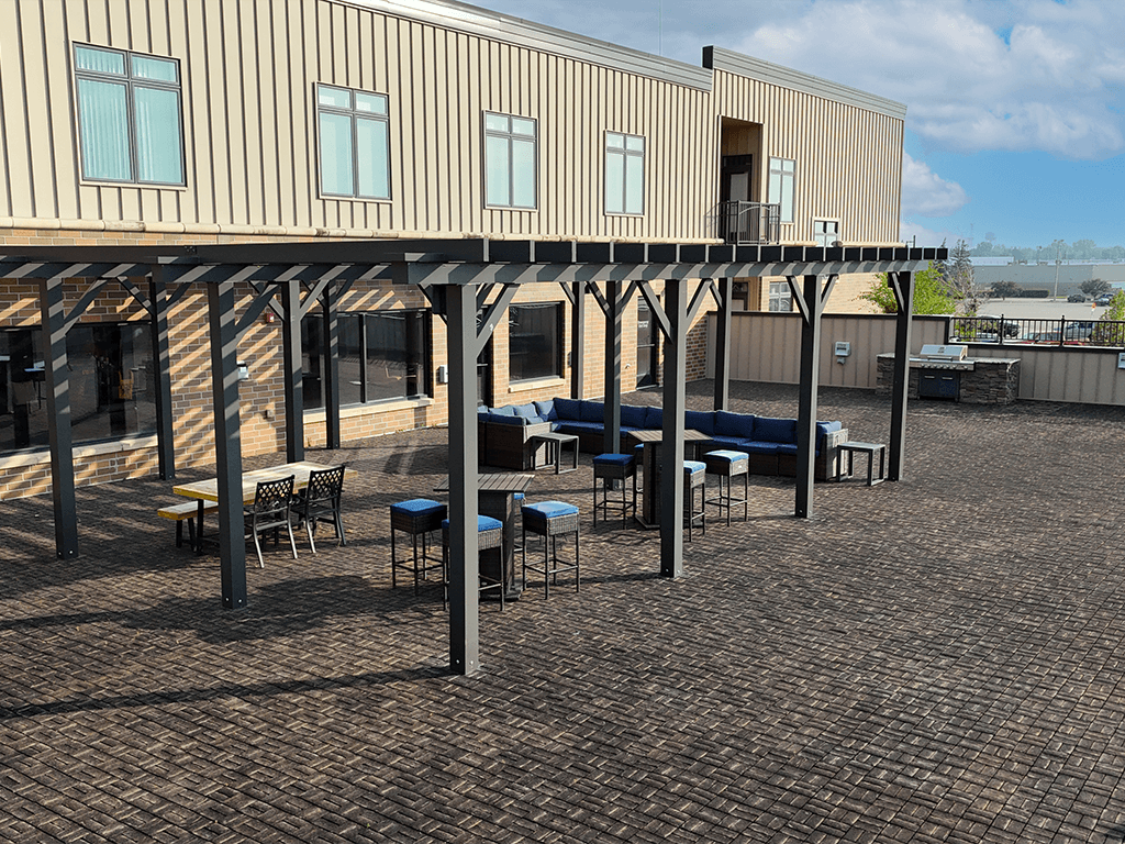 A patio area with tables and chairs is covered by a roof.