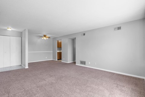 A spacious room with a carpeted floor and a ceiling fan.