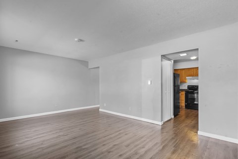 A room with wooden flooring and a white wall with a mirror on the right side.
