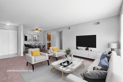 A living room with a white couch, a coffee table, and a television.