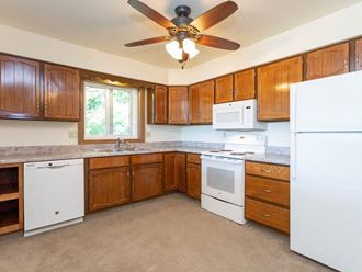 a kitchen with wooden cabinets and a ceiling fan