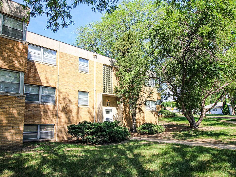 a large brick apartment building with trees in front of it