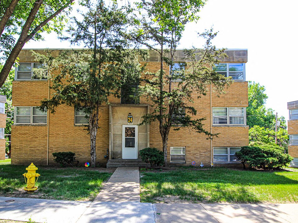 a brick building with a white door and a yellow fire hydrant in front of it