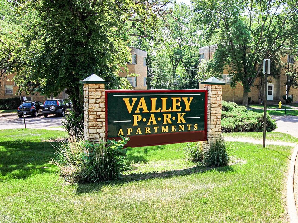 a sign in a grassy area with trees in the background