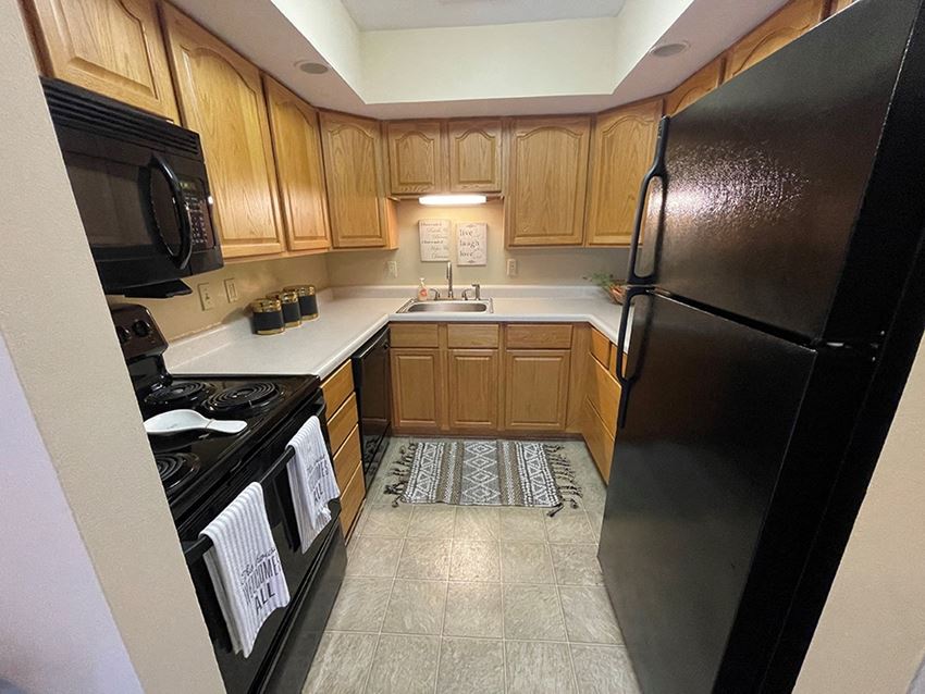 apartment kitchen with black appliances and wooden cabinets - Photo Gallery