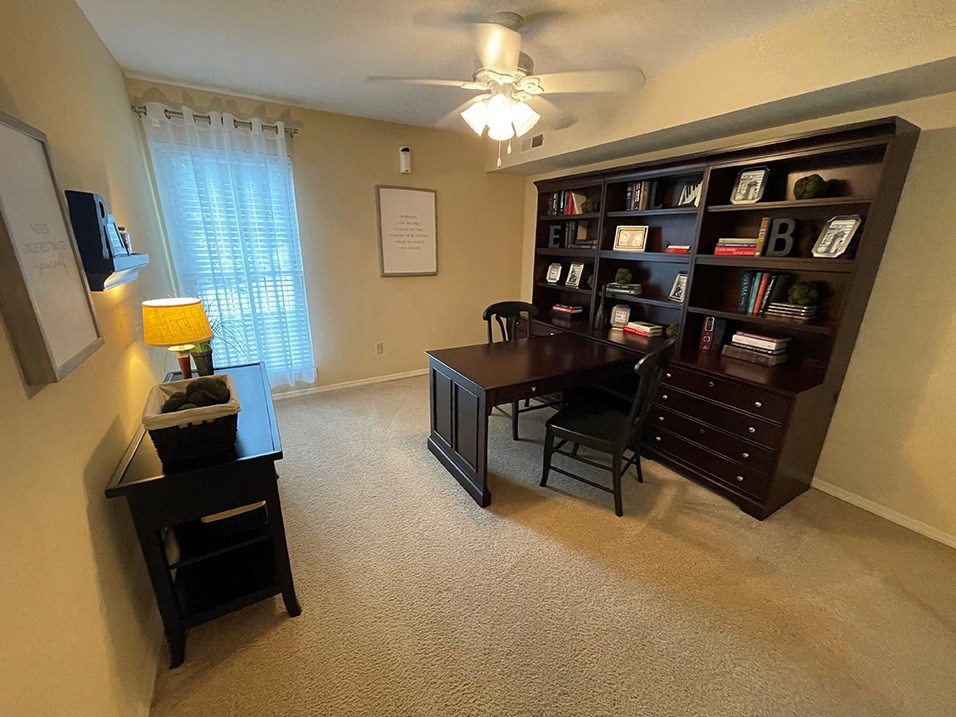 a home office with a desk and a ceiling fan