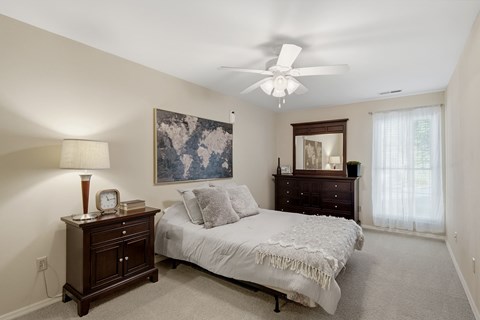 A bedroom with a bed, dresser, and ceiling fan.