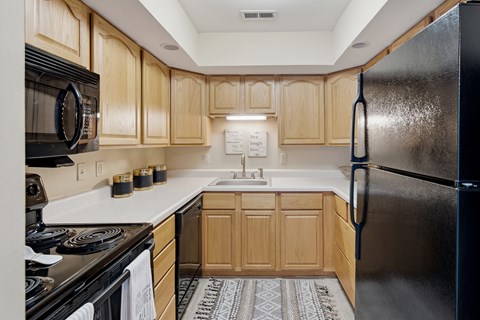 A kitchen with wooden cabinets and a black refrigerator.