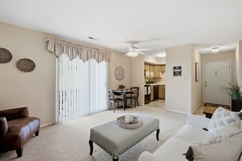 A living room with a brown leather couch, a white sofa, a coffee table, and a dining table with chairs.