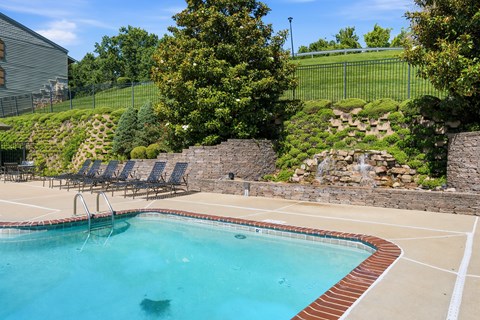 A pool with a waterfall and a stone wall.