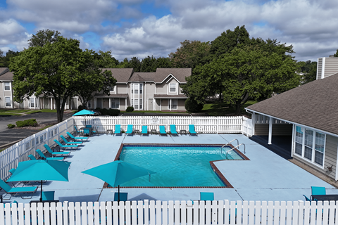 A pool surrounded by a white picket fence with blue umbrellas.