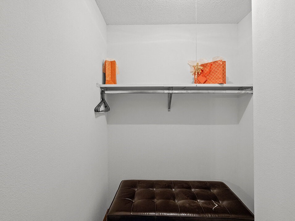 a brown bench in a white room with a shelf