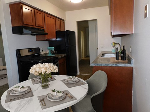 a kitchen and dining area with a white table and chairs and a black refrigerator