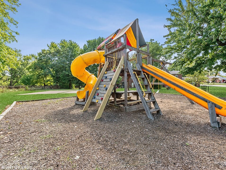 a swing set with a yellow slide in a park