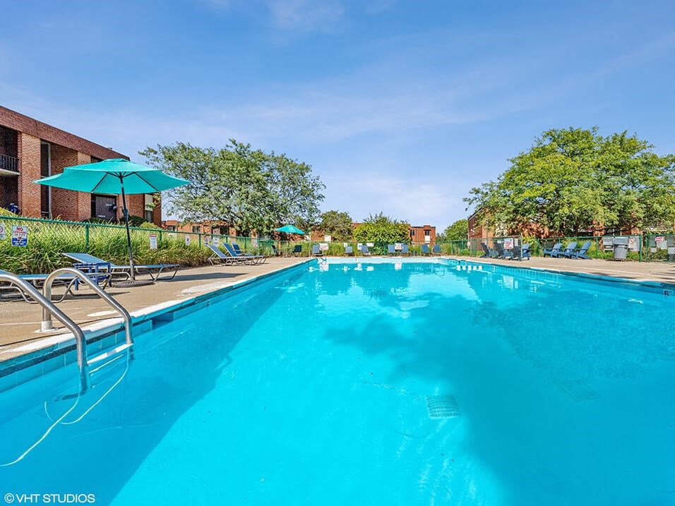 a large blue swimming pool with chairs and umbrellas