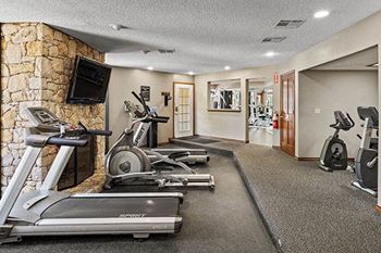 a gym with weights and a tv on a stone wall