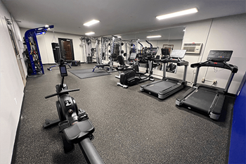 a spacious fitness center with cardio machines and other exercise equipment