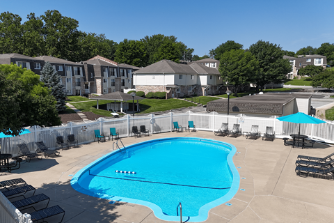 A large swimming pool surrounded by a white fence and lounge chairs.
