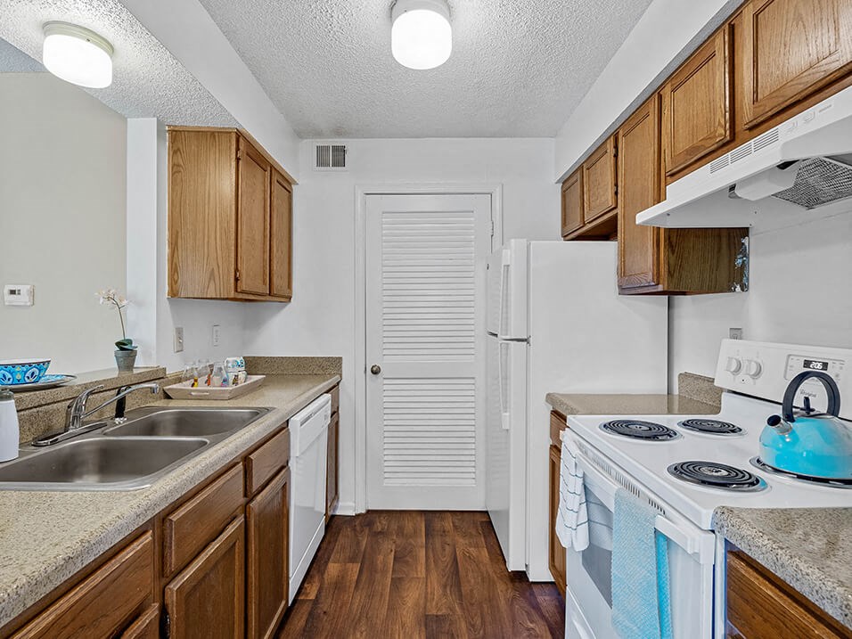 apartment kitchen with a stove, sink, and a refrigerator