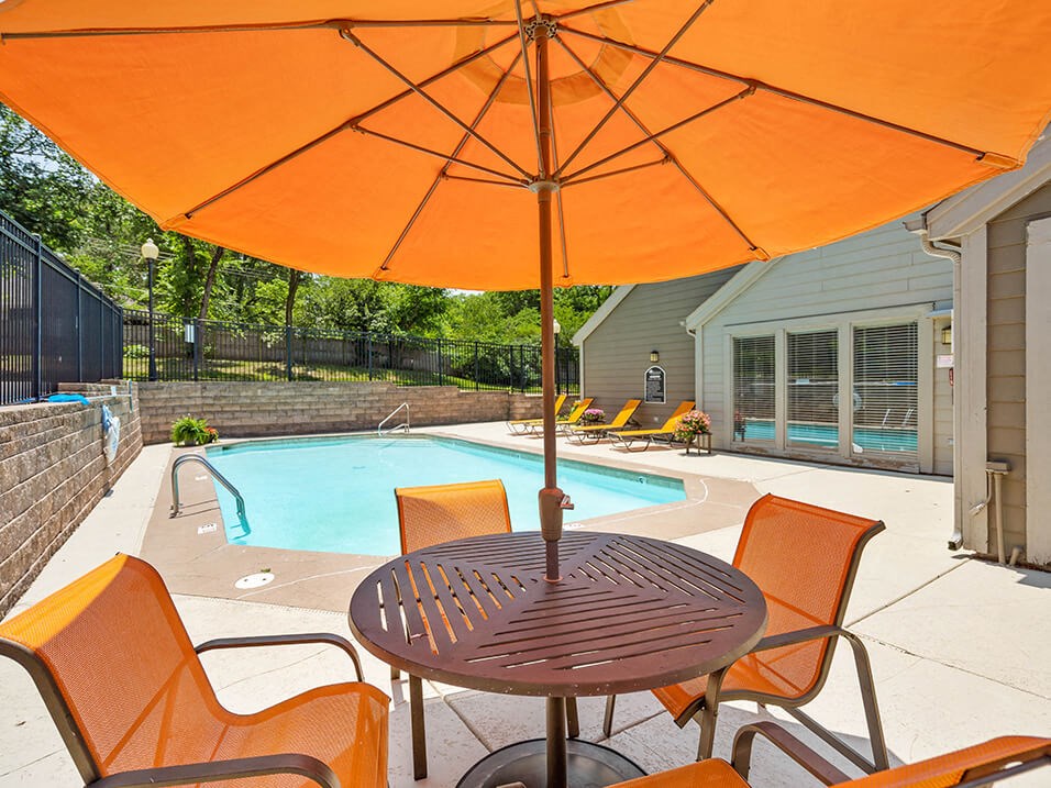 a patio with a pool and a table with an umbrella