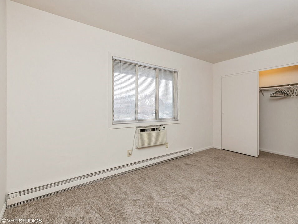 an empty room with a window and a closet