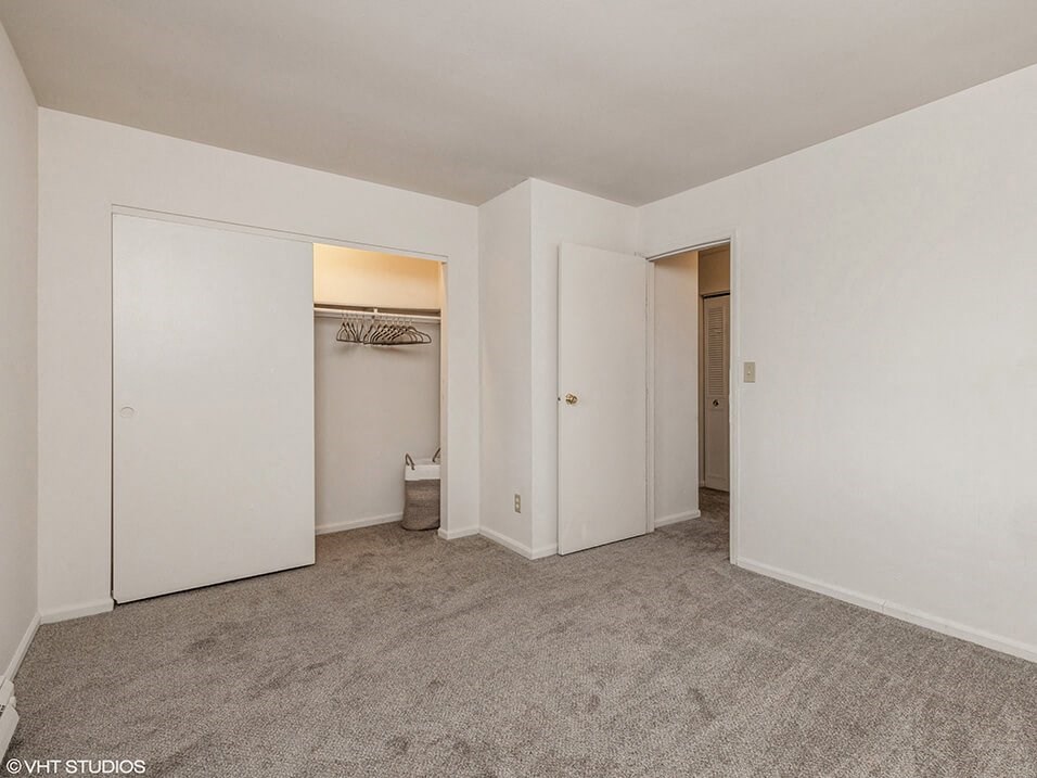 an empty bedroom with white walls and a closet
